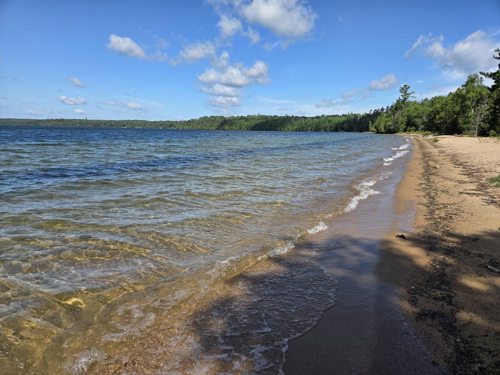 Bernier's Beach shoreline with calm water and trees in the background.